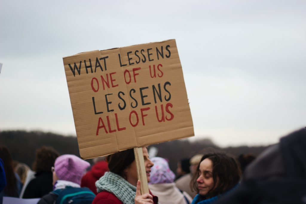 Protest sign: what lessens one of us lessens all of us