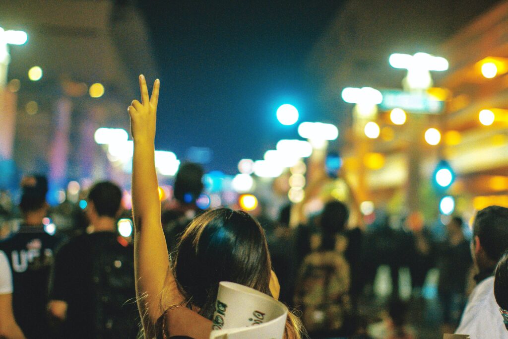 Working as a career professional in a difficult country, young woman holds up a peace sign during a public demonstration/protest