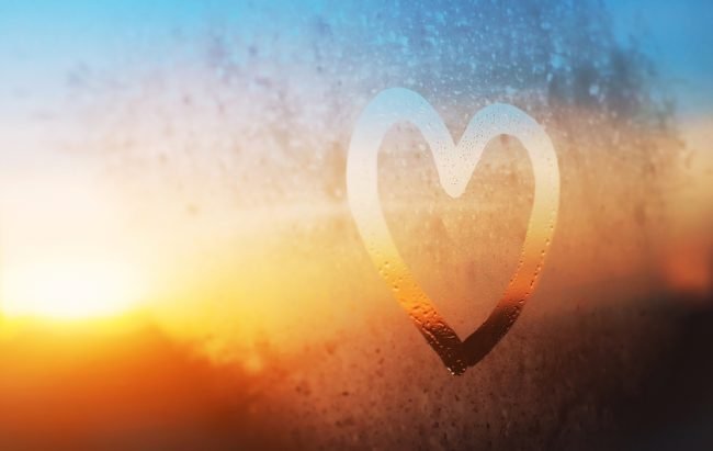 Heart shape traced on foggy window, representing kindness and love.
